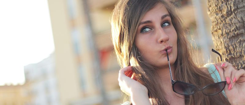 Tips to manage light sensitivity and anxiety Woman looking sideways while holding pair of spectacles